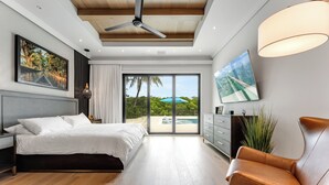 A modern bedroom with a bed, a desk, a chair, and a view of a pool and greenery. - SERENITY ON SUNRISE~Canal Front 5 BR/5.5 Ba New Town Home w/ Pool & Dockage! (Key West)