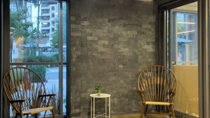 A modern interior with two wooden chairs, a small white table, and a grey brick wall. - ON Brooklin (Sao Paulo)