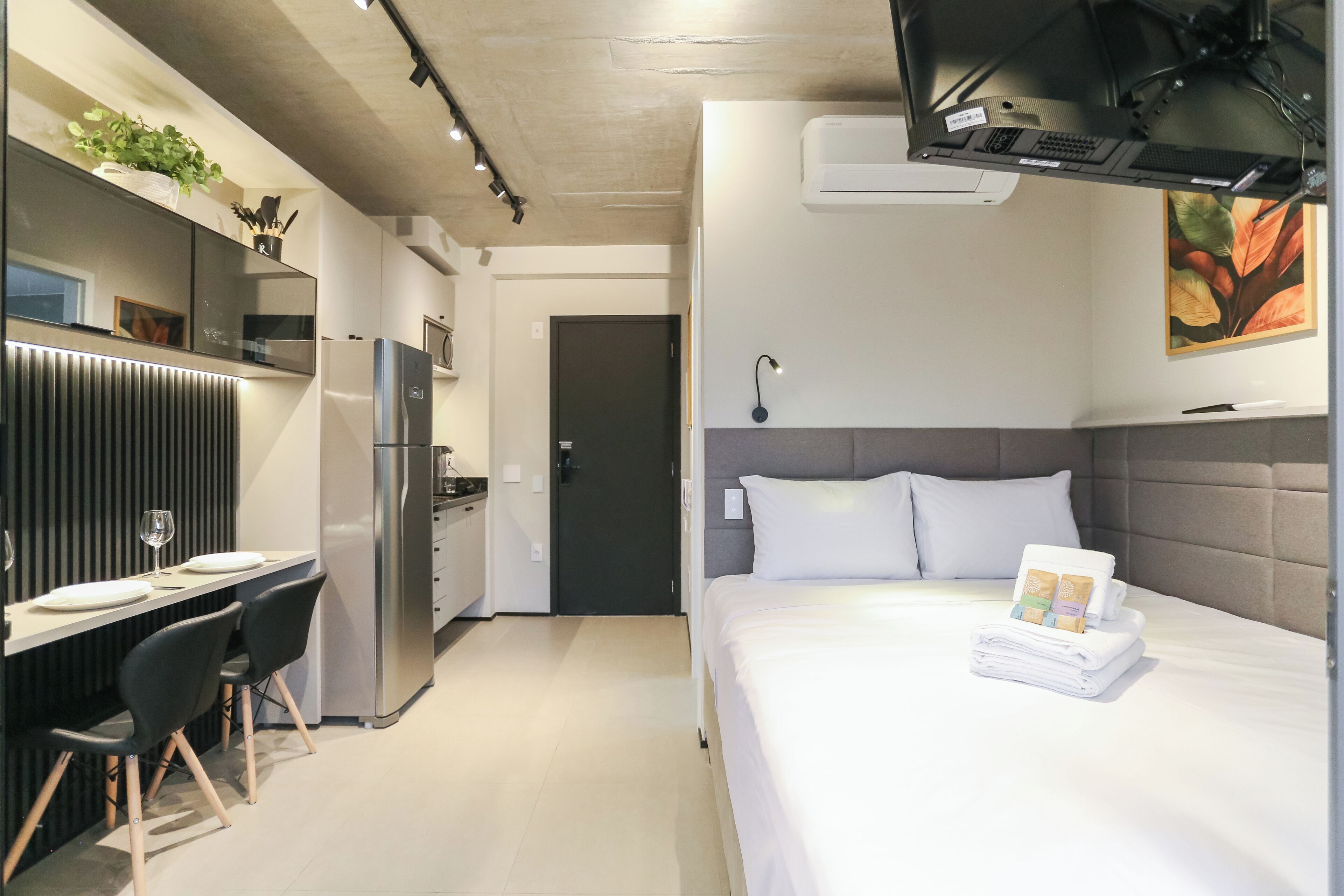Une chambre d’hôtel moderne équipée d’un lit, d’un bureau avec des chaises, d’un réfrigérateur et d’un four à micro-ondes.