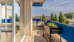 A balcony with a tiled floor, a blue awning, and potted plants. - (033) Le sunny & cosy city trip (Antibes)