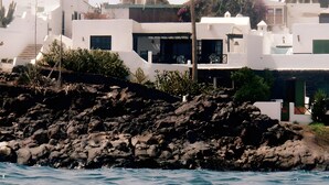 Un edificio costero con paredes blancas, una costa rocosa y palmeras.