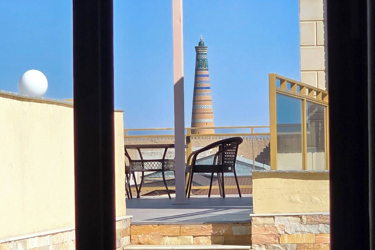 Eine Terrasse mit Blick auf einen hohen Minarett, eine Kugel an einer Wand und eine Glaskonstruktion.