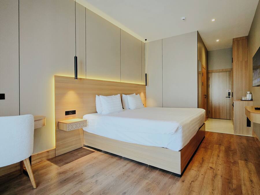 A modern hotel room with a large bed, bedside tables, a desk, and a TV.