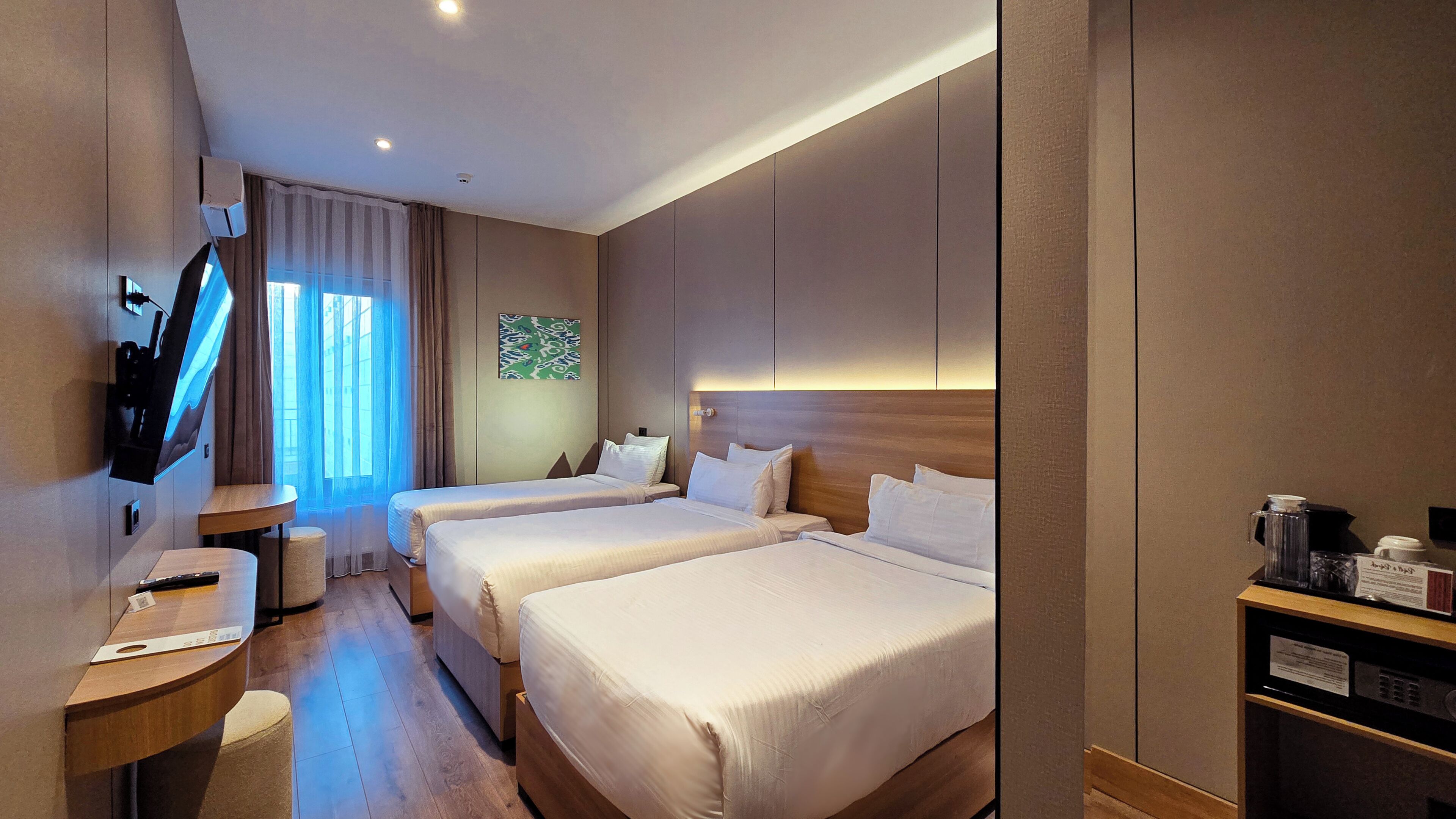A hotel room with two beds, a TV, a desk, and a coffee machine.