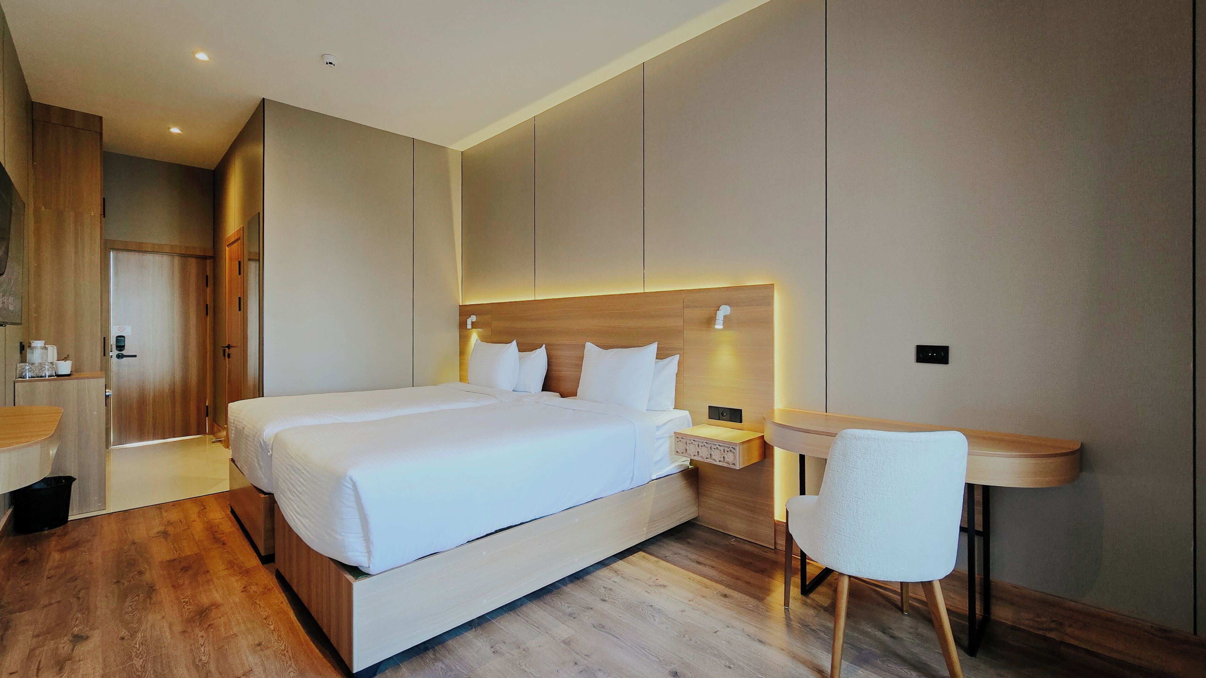 A modern hotel room with a large bed, bedside tables, a desk, and a chair.