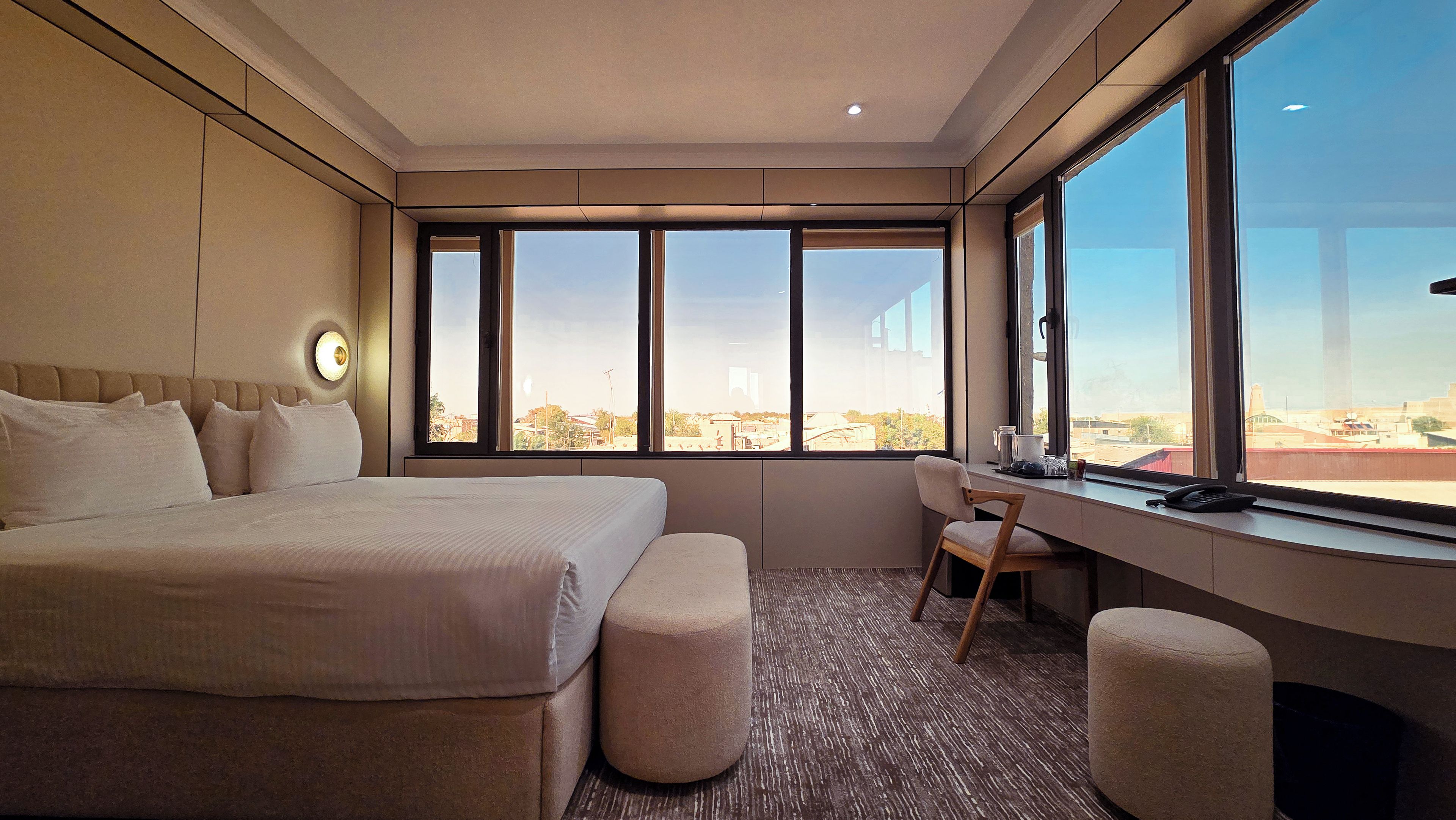 Une chambre d’hôtel avec un grand lit, un bureau et une vue sur la ville.