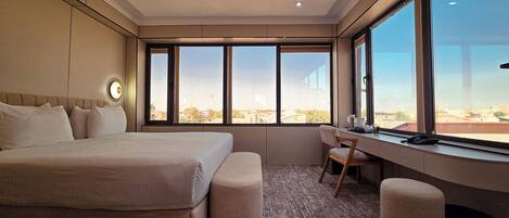 Une chambre d’hôtel avec un grand lit, un bureau et une vue sur la ville.