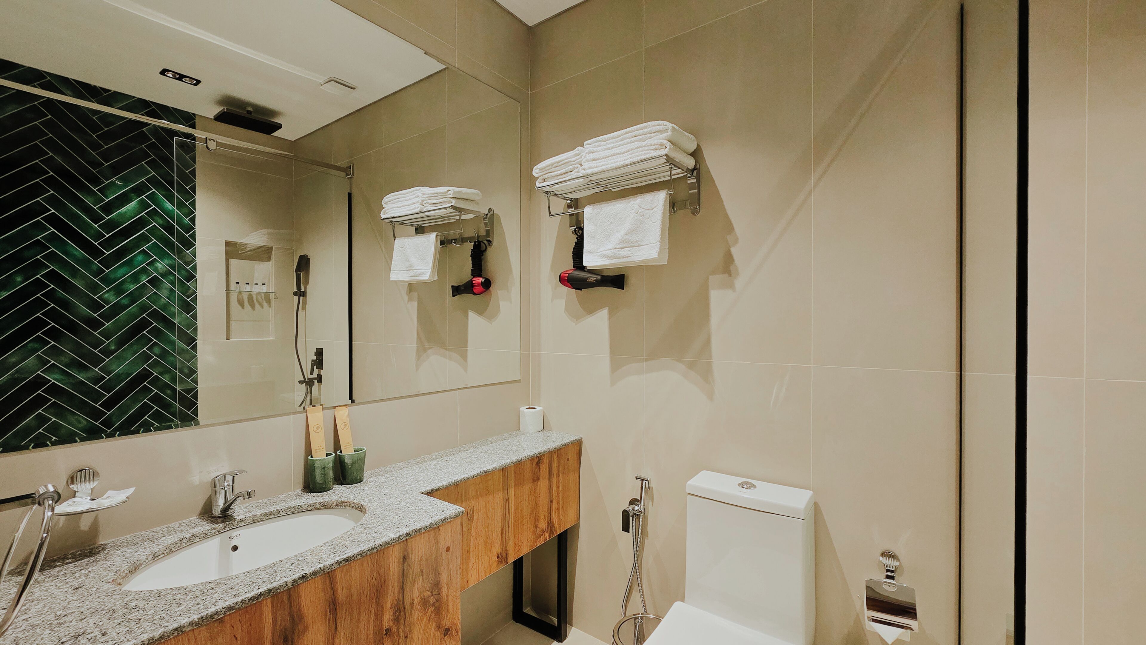 A modern bathroom with a wooden vanity, a large mirror, and two towel racks.