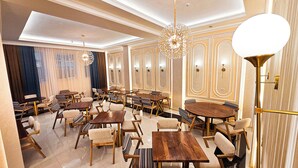 Un comedor amplio con varias mesas y sillas, paneles de pared elegantes y lámparas decorativas.