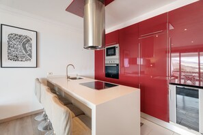 A modern kitchen with a central island, stainless steel appliances, and red cabinetry. - Vacation Apartment '3 Bedrooms Heated Pool' with Sea View, Private Terrace & Wi-Fi (Costa Adeje)