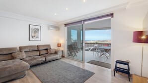 A modern living room with a sofa, a rug, a lamp, and a view through a glass door to an outdoor area.