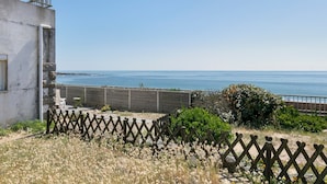 A coastal property with a view of the sea, a fenced garden, and a building with a balcony. - Holiday Home 'Villa Timao Plage' with Sea View, Private Terrace and Wi-Fi (Batz-sur-Mer)