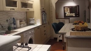 Une cuisine équipée d’un lave-linge, d’un évier et d’un plan de travail sur lequel se trouvent divers objets.