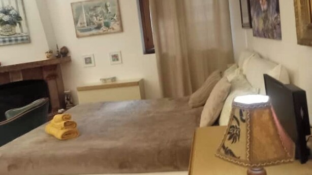 Een slaapkamer met een bed, een lamp en een schilderij aan de muur.
