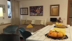 Een hotelkamer met een bed, een eettafel met fruit en een televisie.