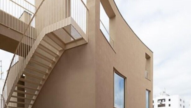 Un edificio moderno dall'architettura originale, caratterizzato da una scala a chiocciola e numerose finestre.