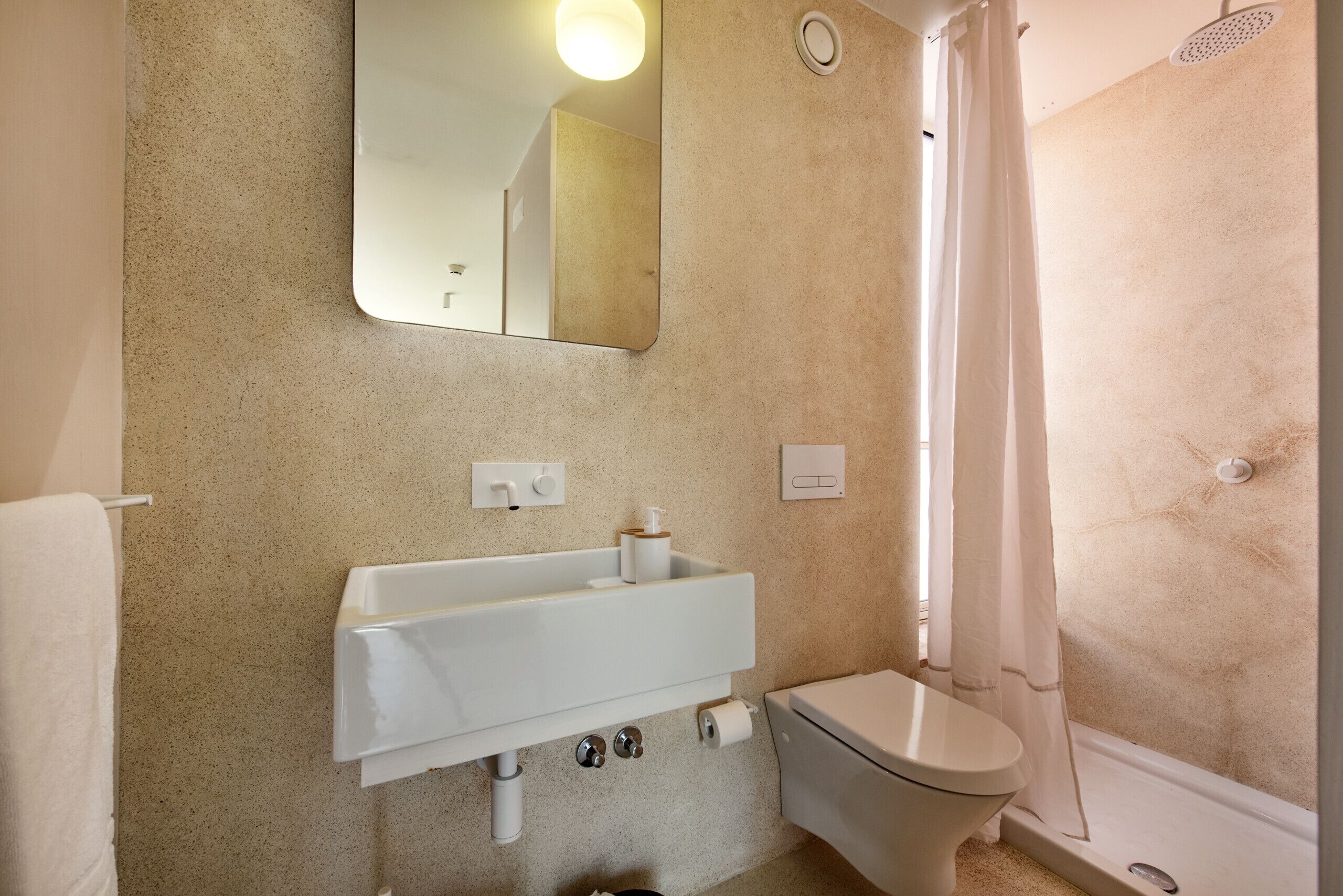 Un baño con lavamanos, inodoro y cortina de ducha blancos.