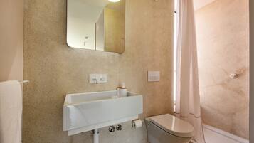 Un baño con lavamanos, inodoro y cortina de ducha blancos.