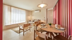 A modern living room with a dining area, featuring a sofa, chairs, a table, and a lamp.