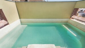 A rectangular swimming pool with clear water, surrounded by a low wall and a small set of steps leading into the pool.