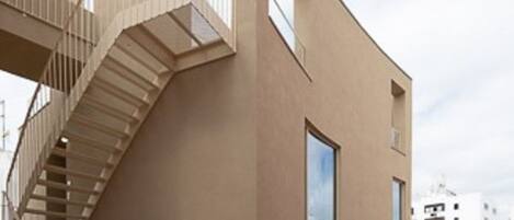 Un edificio moderno con un diseño angular distintivo, que presenta una escalera en espiral y múltiples ventanas.