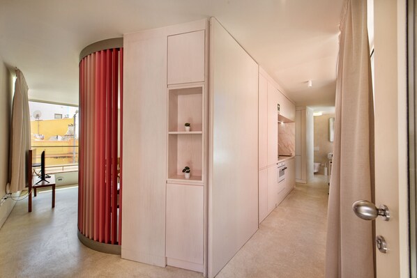 Habitación de hotel moderna con puerta corrediza, un pequeño rincón de descanso con una silla y vistas al exterior.