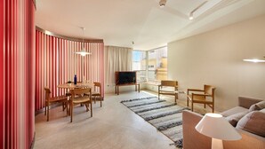 Ein modernes Wohnzimmer mit Essbereich, Fernseher und Sofa.