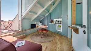 A compact kitchen with a dining area, wooden flooring, and a view through a large window. - PG - 1EA - Studio Superior - Palacete do Guadiana (Vila Real Santo Antonio)