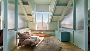 A cozy room with a large window, a round rug, a bed, and a small table. - PG - 1EA - Studio Superior - Palacete do Guadiana (Vila Real Santo Antonio)