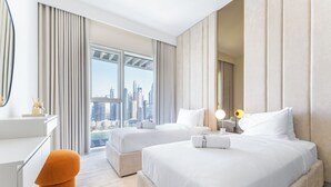 Une chambre d’hôtel avec deux lits, un bureau, une chaise et une vue sur le panorama urbain.