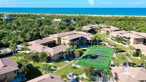 Ein Resort mit mehreren Gebäuden, einem Tennisplatz und Blick auf den Strand.
