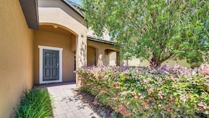 A building with a beige exterior, a paved pathway, and a variety of shrubs and plants. - 17 Mi to Disney: Getaway in Davenport w/ Game Room (Davenport)