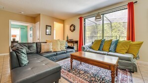 A living room with a sectional sofa, a coffee table, and a window with curtains. - 17 Mi to Disney: Getaway in Davenport w/ Game Room (Davenport)