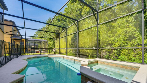 An indoor swimming pool with clear glass walls, a hot tub, and a covered patio area. - 17 Mi to Disney: Getaway in Davenport w/ Game Room (Davenport)