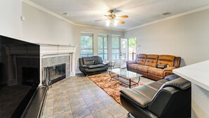 A spacious living room with a fireplace, leather sofas, and a ceiling fan. - DFW Sports Hub: Home w/ Pool & Hot Tub in Frisco! (Frisco)