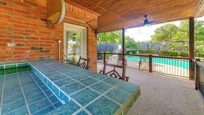 A covered patio area with a pool, brick walls, and outdoor seating. - DFW Sports Hub: Home w/ Pool & Hot Tub in Frisco! (Frisco)
