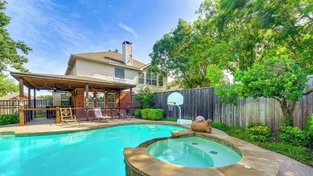 A backyard with a swimming pool, hot tub, and a covered patio area with outdoor furniture. - DFW Sports Hub: Home w/ Pool & Hot Tub in Frisco! (Frisco)