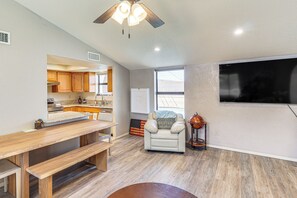 A modern kitchen with wooden cabinets, a dining table, and a ceiling fan.