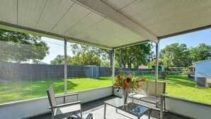 A covered patio area with a table and chairs, a vase with flowers, and a view of a grassy yard and trees. - 7 Mi to Busch Gardens: Tampa Gem w/ Yard! (Tampa)