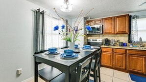 A kitchen with wooden cabinets, a microwave, and a dining table set with blue bowls and a vase with branches. - 7 Mi to Busch Gardens: Tampa Gem w/ Yard! (Tampa)