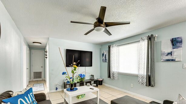 A living room with a white coffee table, grey sofa, and a ceiling fan. - 7 Mi to Busch Gardens: Tampa Gem w/ Yard! (Tampa)