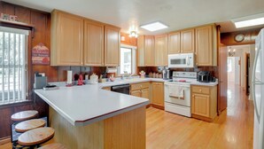A kitchen with wooden cabinets, a central island, a microwave, and a refrigerator. - Private 3-acre Retreat w/ Game Room in Bunnell! (Bunnell)