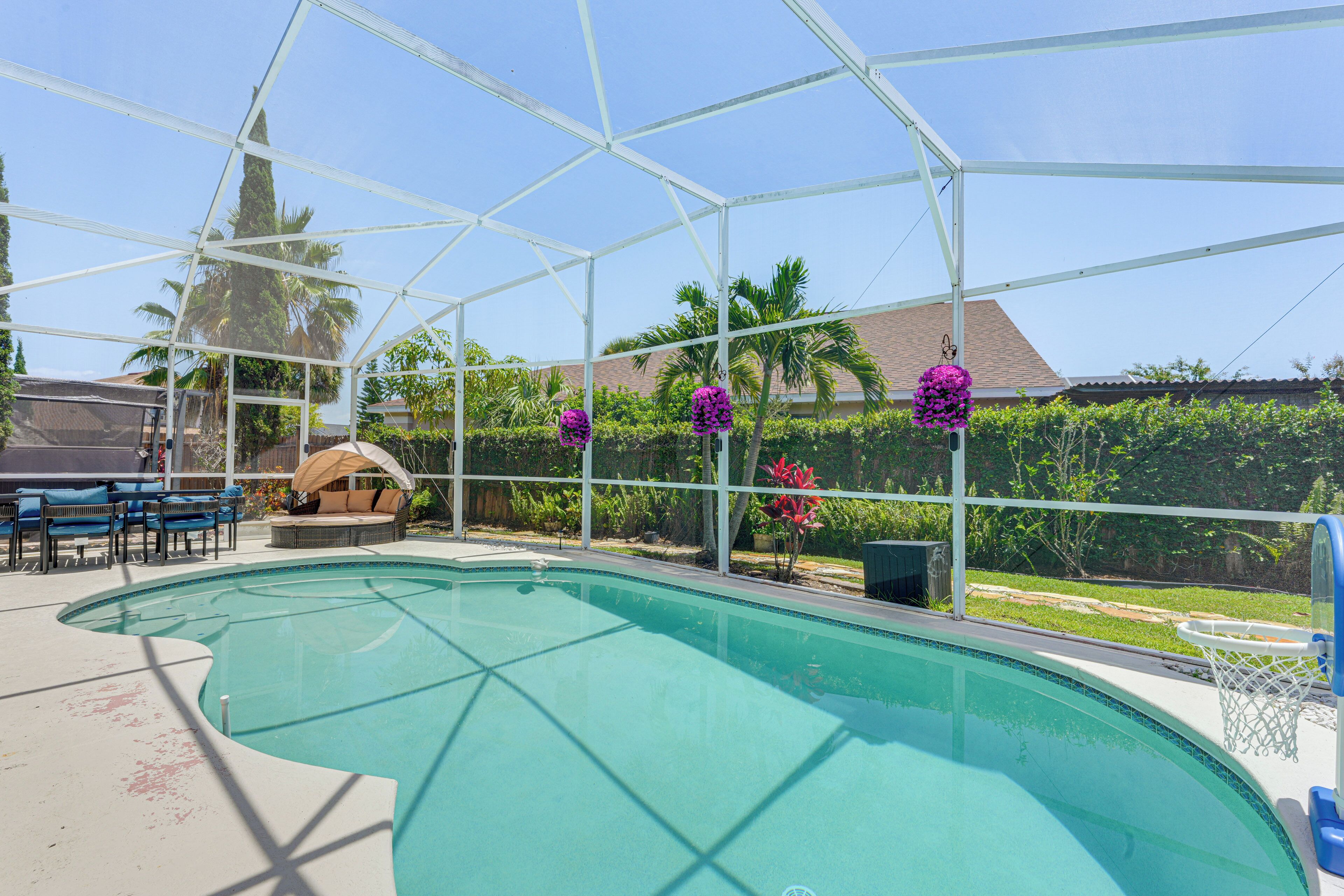 A covered swimming pool with a clear view of the surrounding greenery and a patio area with seating.