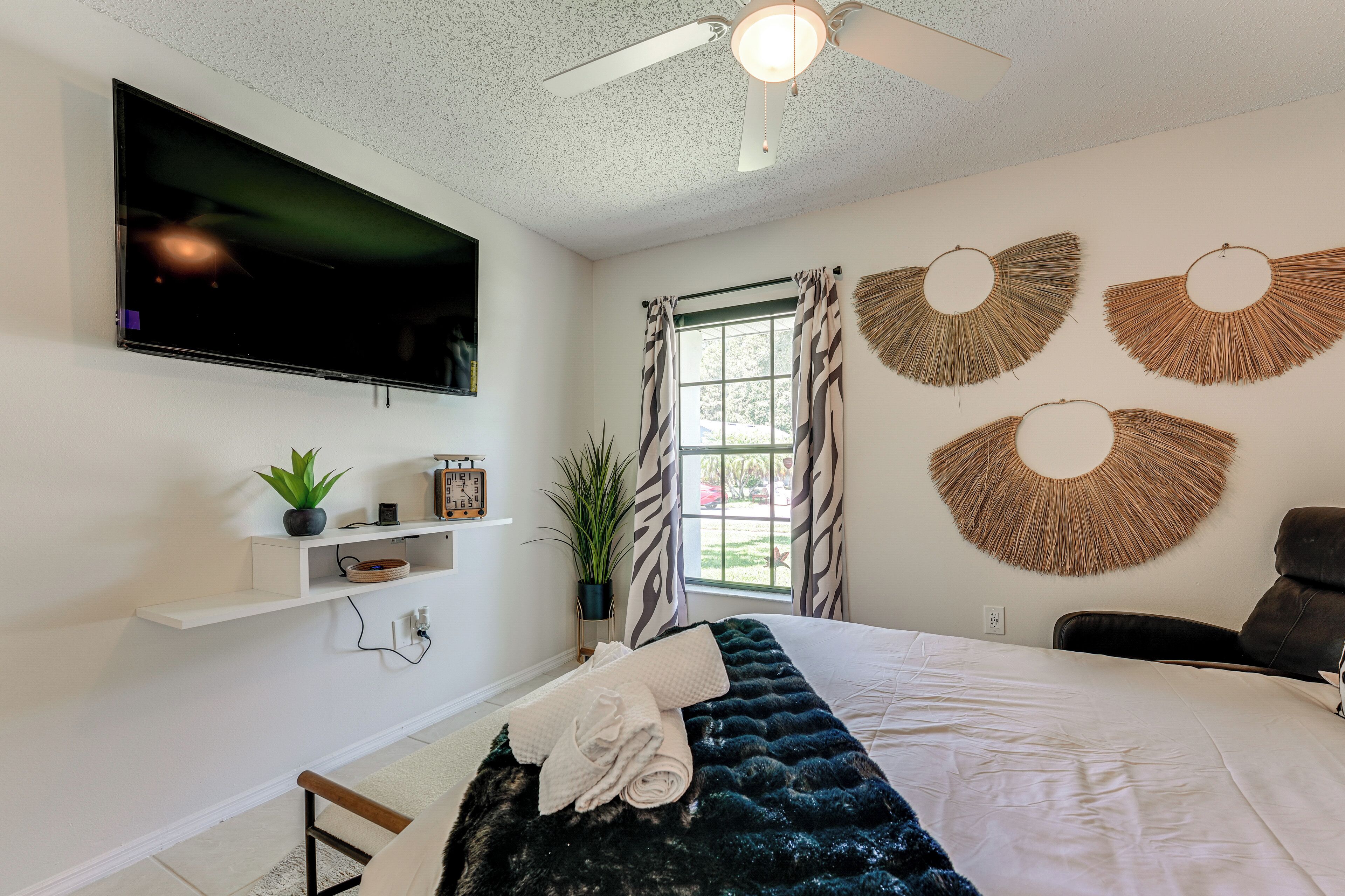 Camera da letto moderna con un letto grande, una TV a schermo piatto montata a parete, una ventola a soffitto e decorazioni murali.