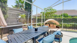A covered patio area with a table and chairs, a hot tub, and a view of the surrounding garden and houses. - Disney Getaway w/ Private Hot Tub 14 Mi to Parks (Kissimmee)