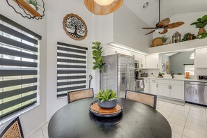 Eine moderne Küche mit weißen Schränken, einem Edelstahlkühlschrank und einem Essbereich mit rundem Tisch und Stühlen.