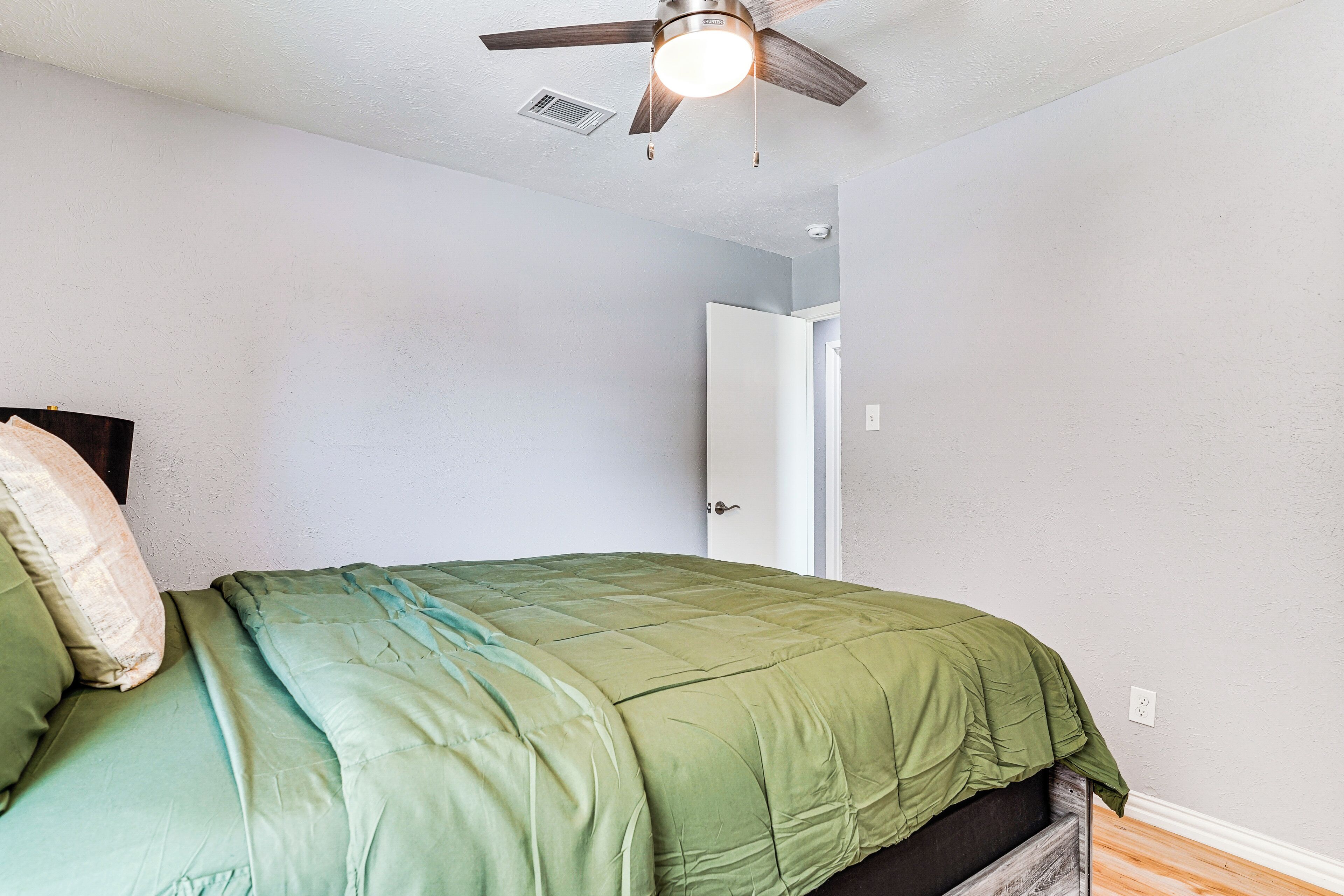 A bedroom with a bed, a ceiling fan, and a door.