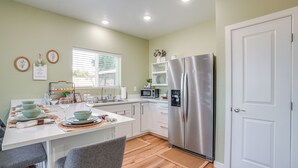 A modern kitchen with white cabinets, a stainless steel refrigerator, and a dining area with a table set for four.