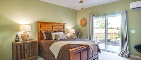 A bedroom with a bed, nightstands, a ceiling fan, and a view through a sliding glass door.