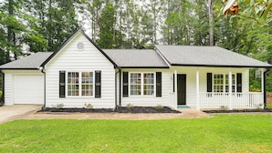 A single-story house with a white exterior, black shutters, and a small porch.